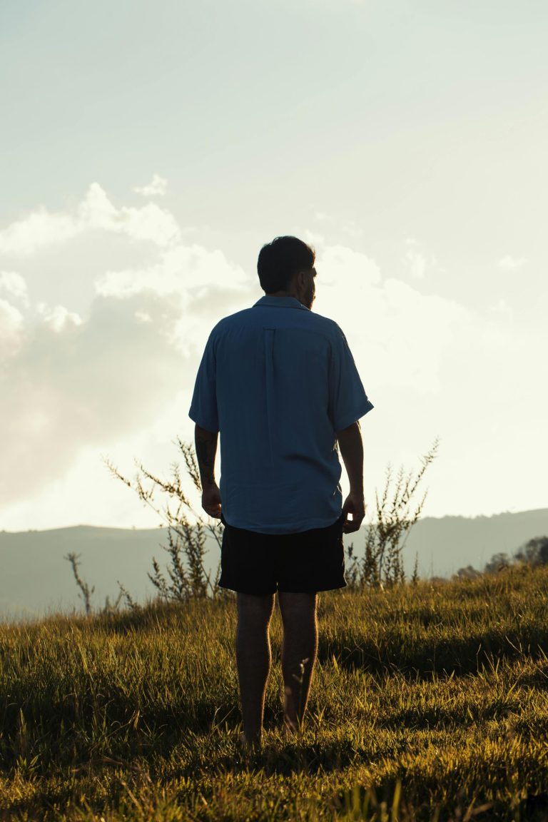 Man standing on a grassy knoll looking at the vista having conquered drug and alcohol addiction.