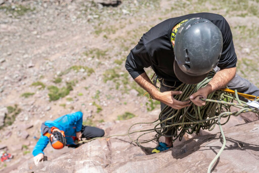 Overhead shot of two men rock climbing and supporting each other.