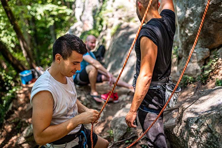 Group of men outside setting up to do some rock climbing.