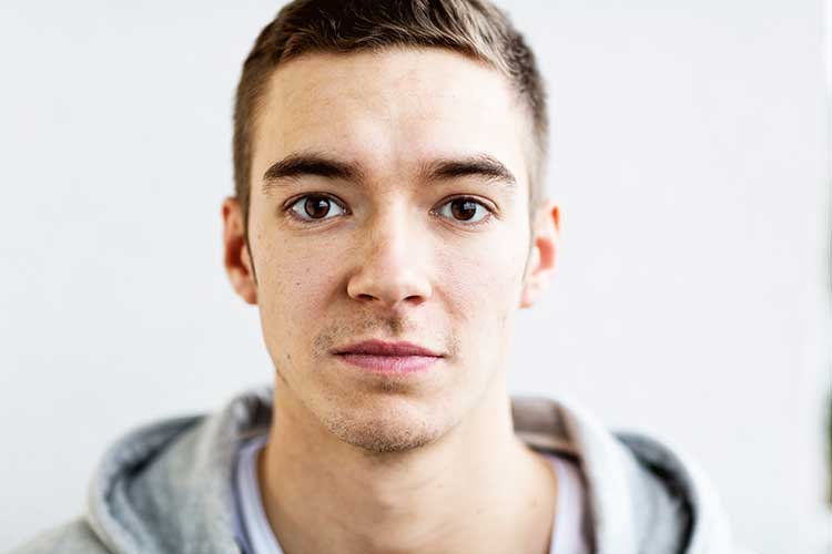 Young man looking into camera reluctant to get help for his drug and alcohol addiction.