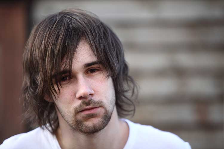 Despondent man looking at camera who refuses to get mental health help.