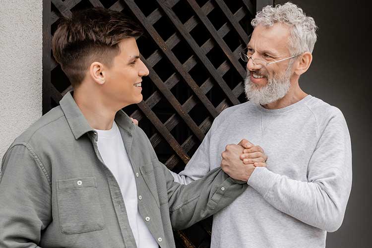 Father gripping son's hand pleased to see him out of drug rehab.