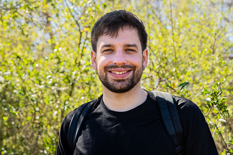 Photo of a man smiling outside with backpack having gone through alcohol detox.