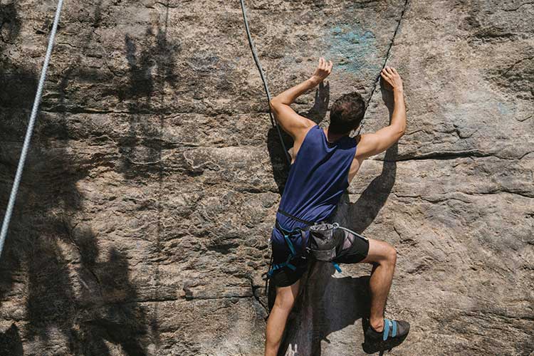 Man rock climbing prior to a outdoor cognitive behavioral therapy session.