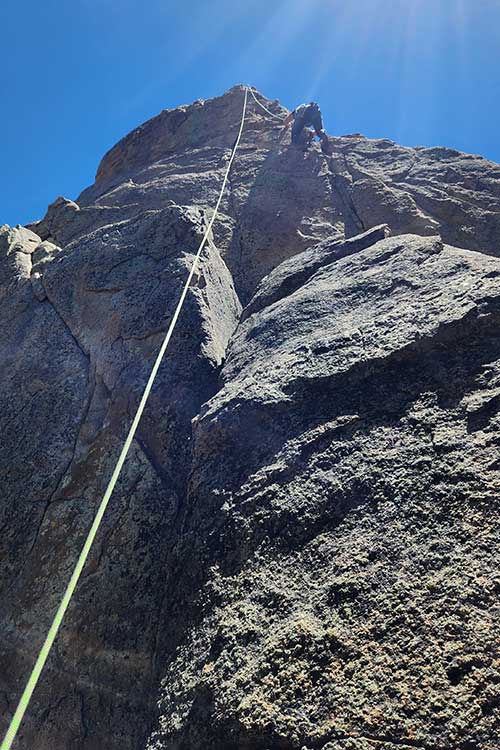 Below view of man rock climbing as part of the outdoor process of addiction treatment in Vista, CA.