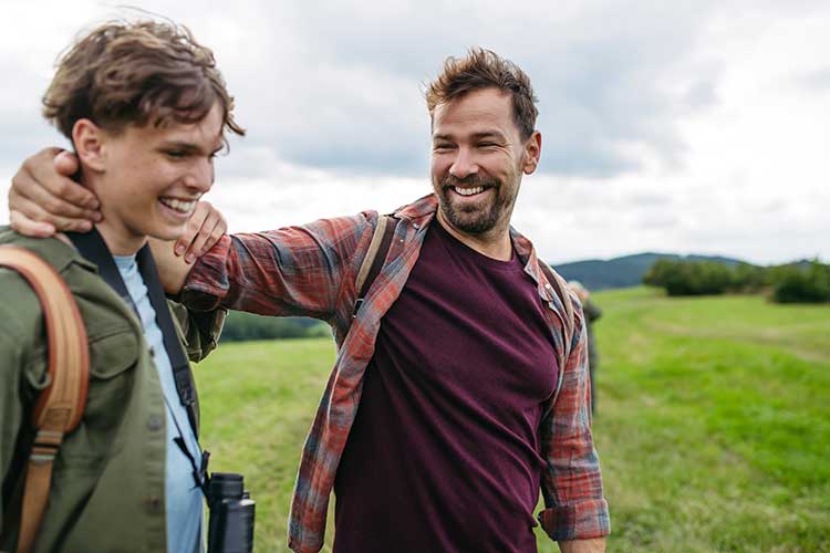 Father with his arm on his sons shoulder smiling as they move past son's drug and alcohol addiction.