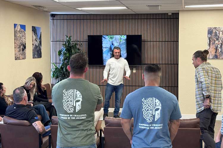 Group session at Sacred Journey Recovery with men standing and seated in a room during a discussion.
