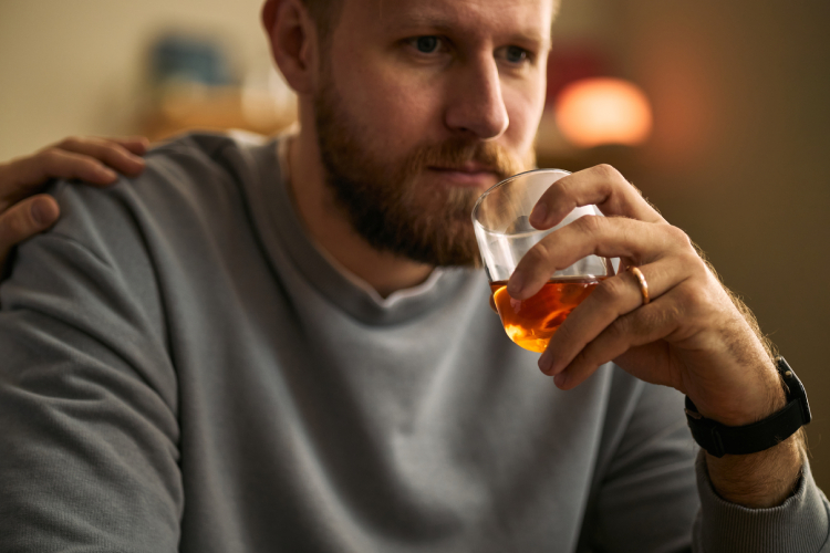Man alone at a bar holding a whiskey glass, reflecting on the tipping point of high functioning drinking