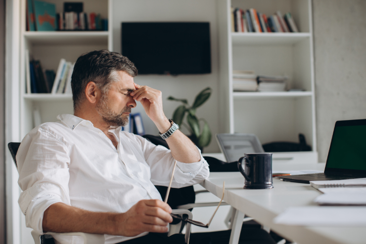Tired office worker slumped at desk with coffee, struggling to focus after stimulant use erodes productivity