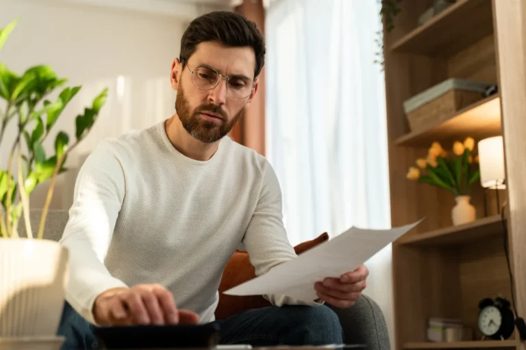 Person reviewing rehab insurance statement and calculator to compare out-of-pocket costs versus covered treatment expenses