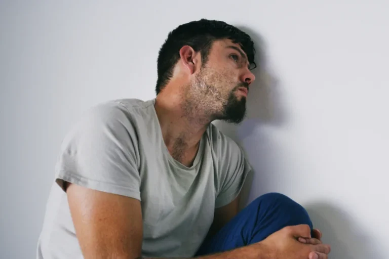 Person sitting alone looking pensive, reflecting the lingering opioid cravings after withdrawal fades