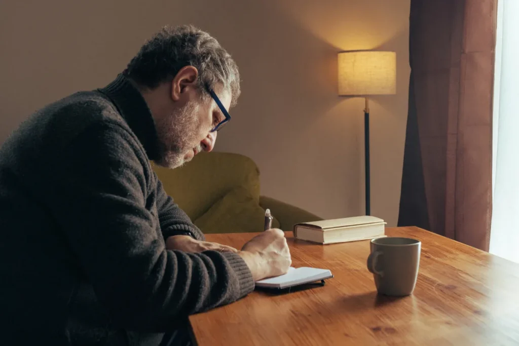 Man after CBT session writing down in journal, mapping triggers and thoughts rather than just talking about feelings