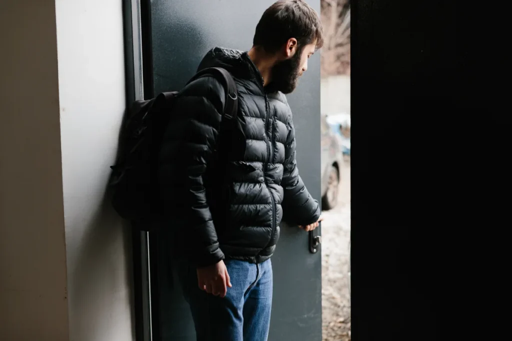 Person leaving treatment center with a backpack, to return home after treatment during the crucial first month